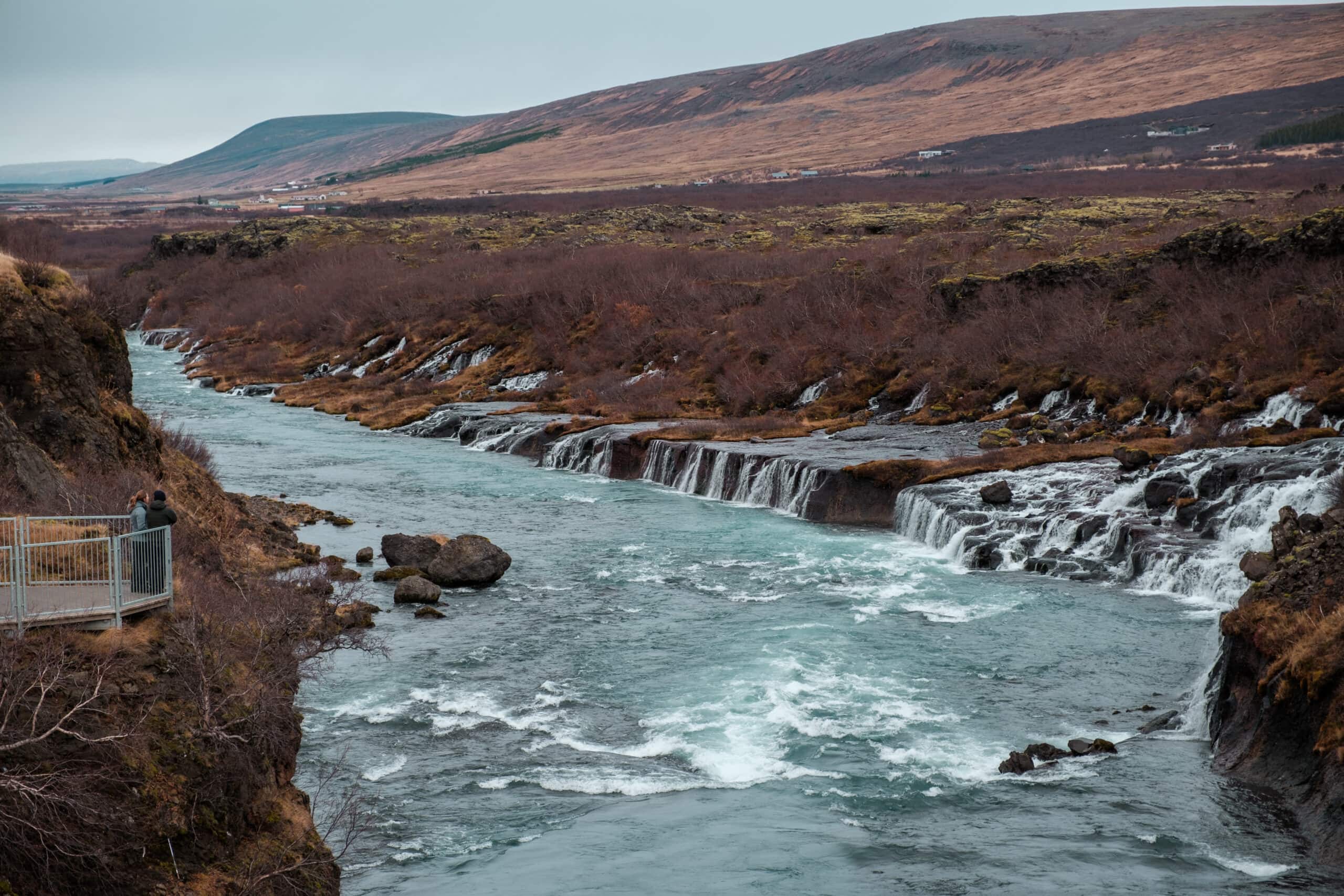Hraunfossar spills over a hill in a series of waterfalls.
