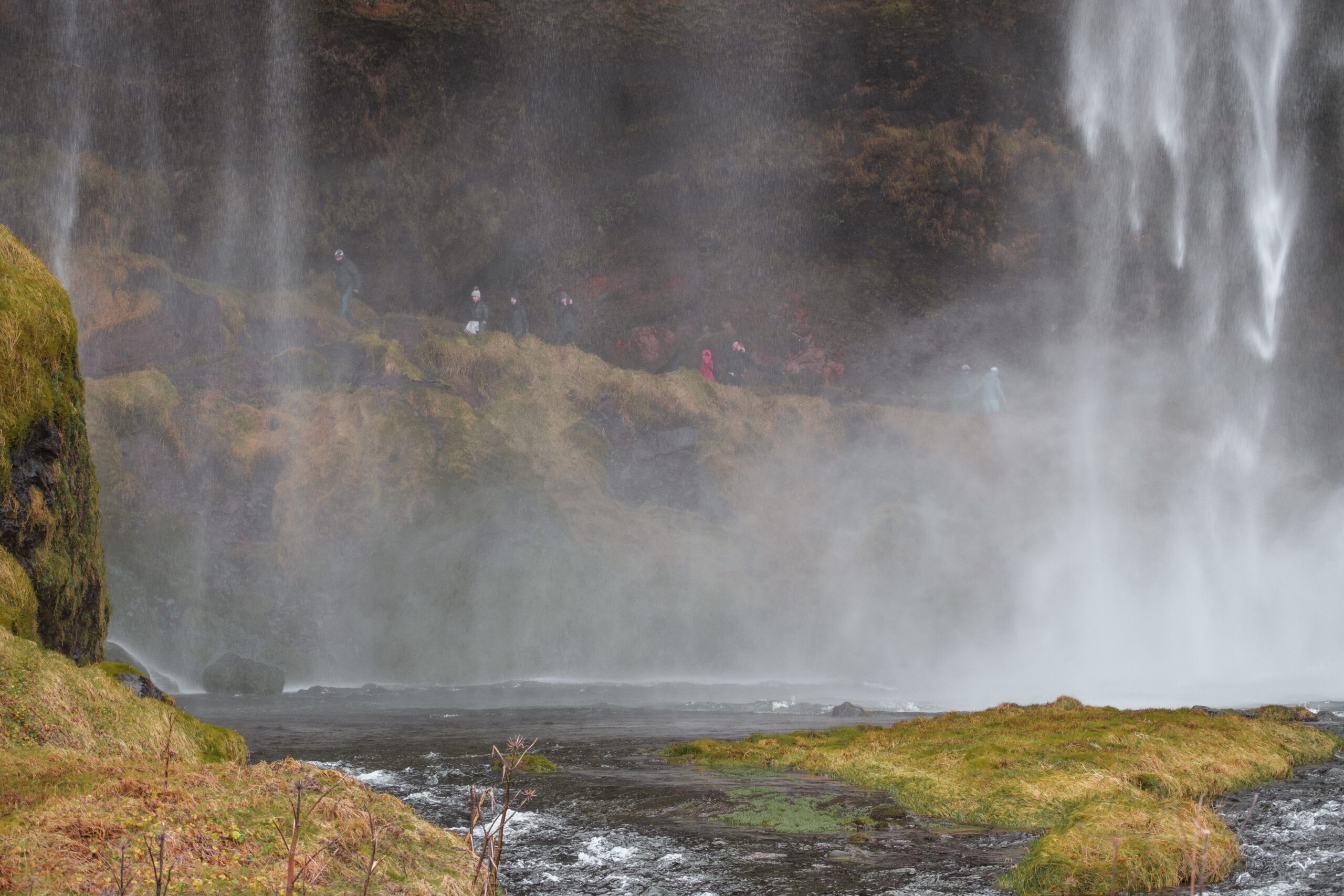 People walk behind Seljalandsfoss.