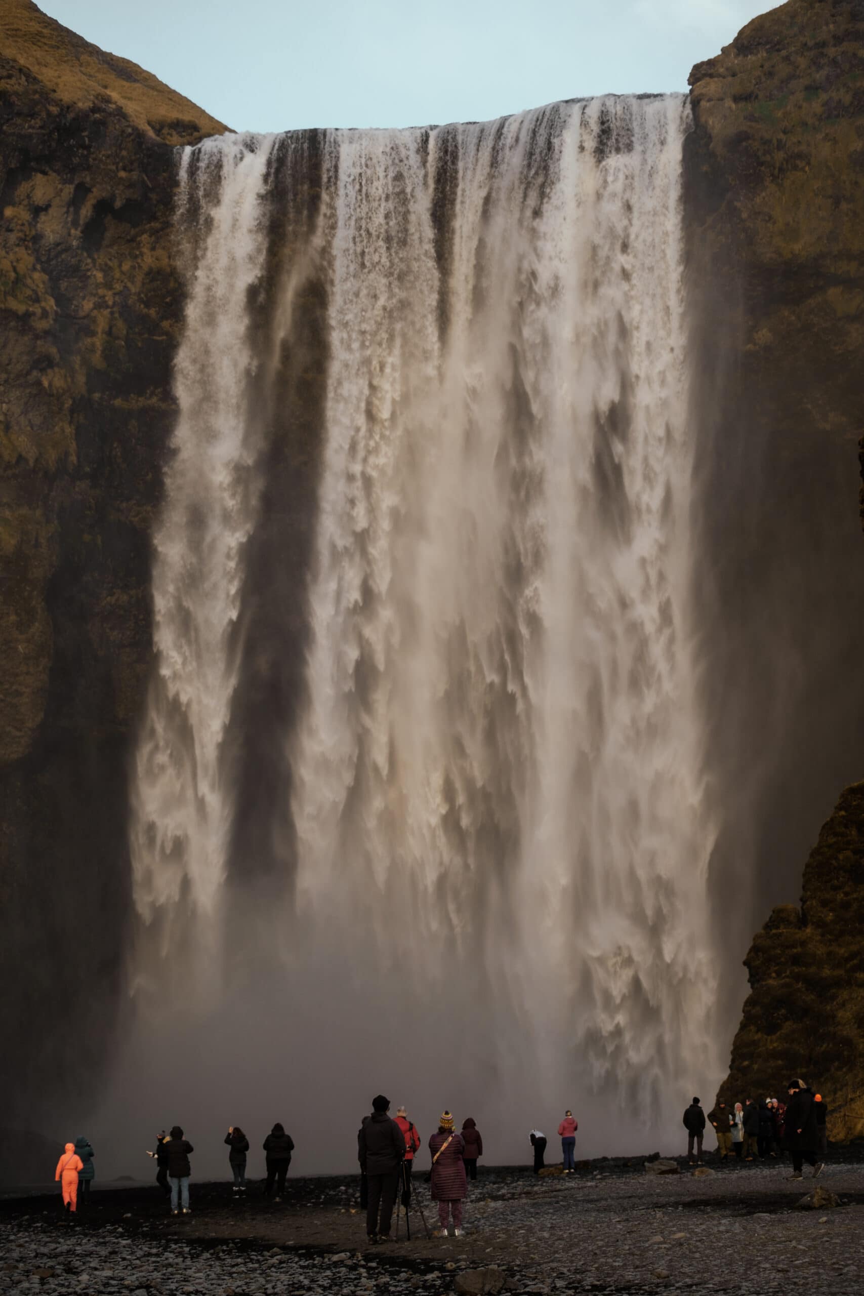 People stand in front of Skogafoss.