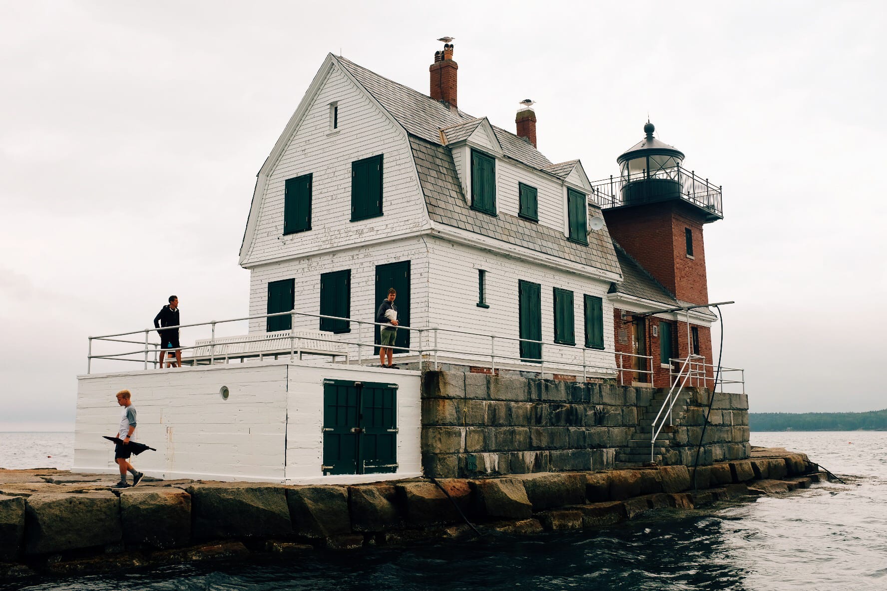 People walking around the Rockland Breakwater Lighthouse.