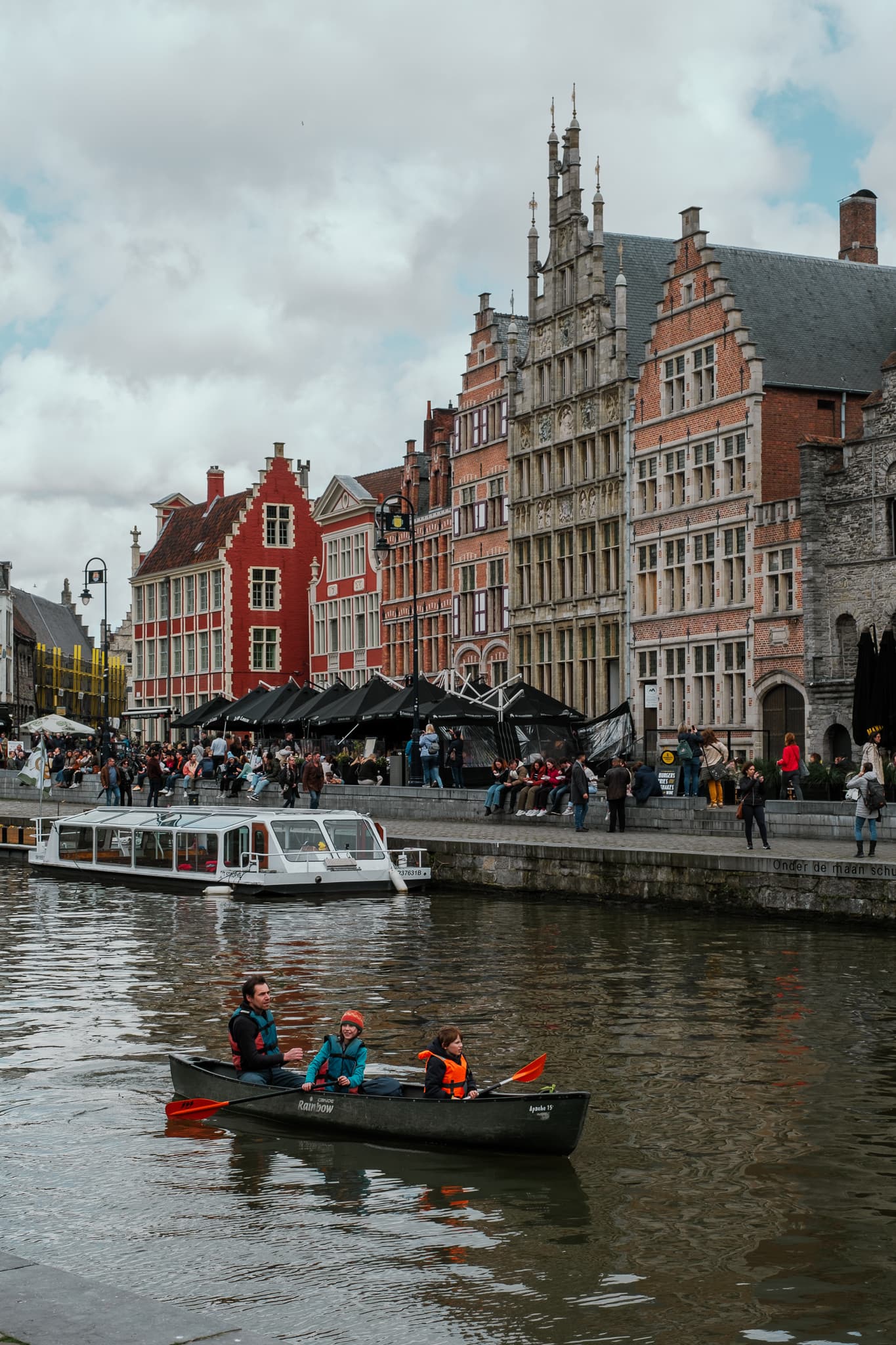 People ride a canoe between Graslei and Korenlei.