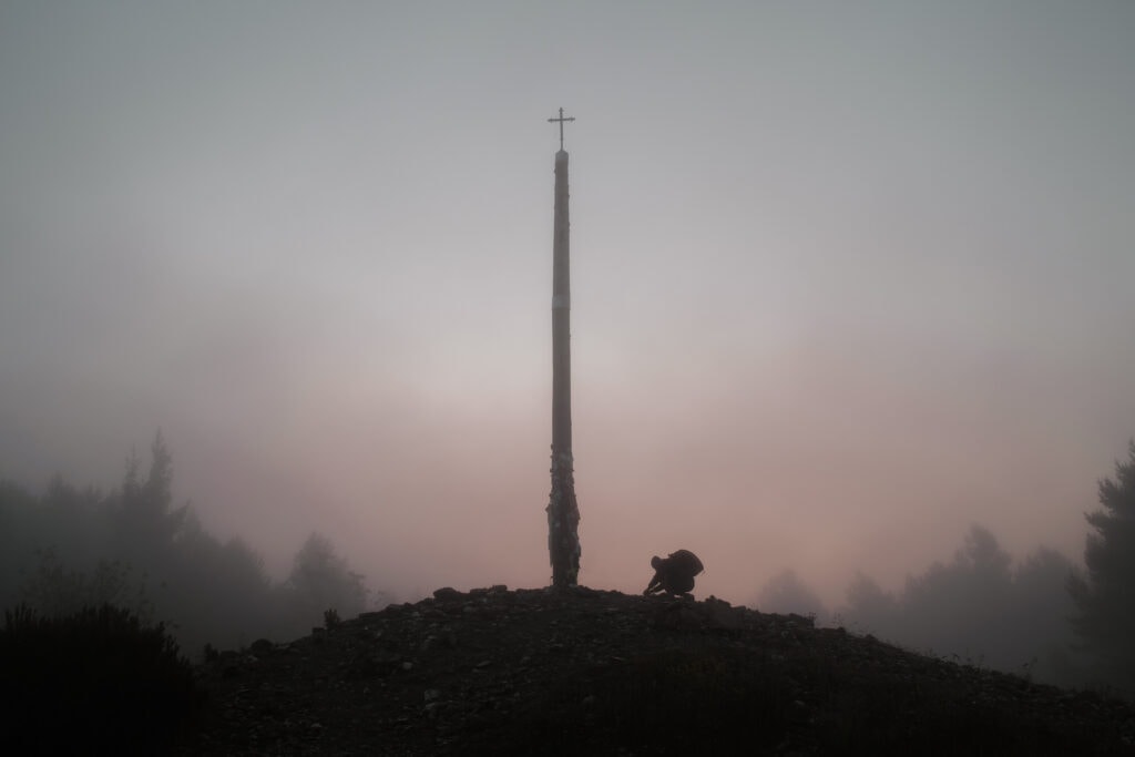 A pilgrim places a stone at Cruz de Ferro.
