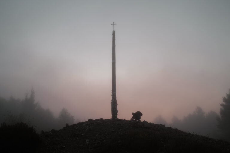 A pilgrim lays down a stone at Cruz de Ferro.