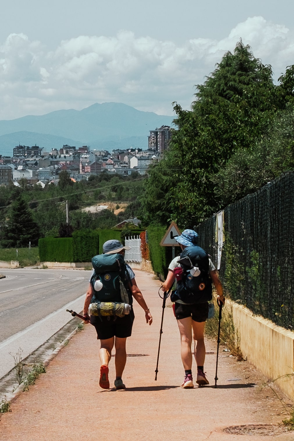 Two pilgrims walk toward Ponferrada.