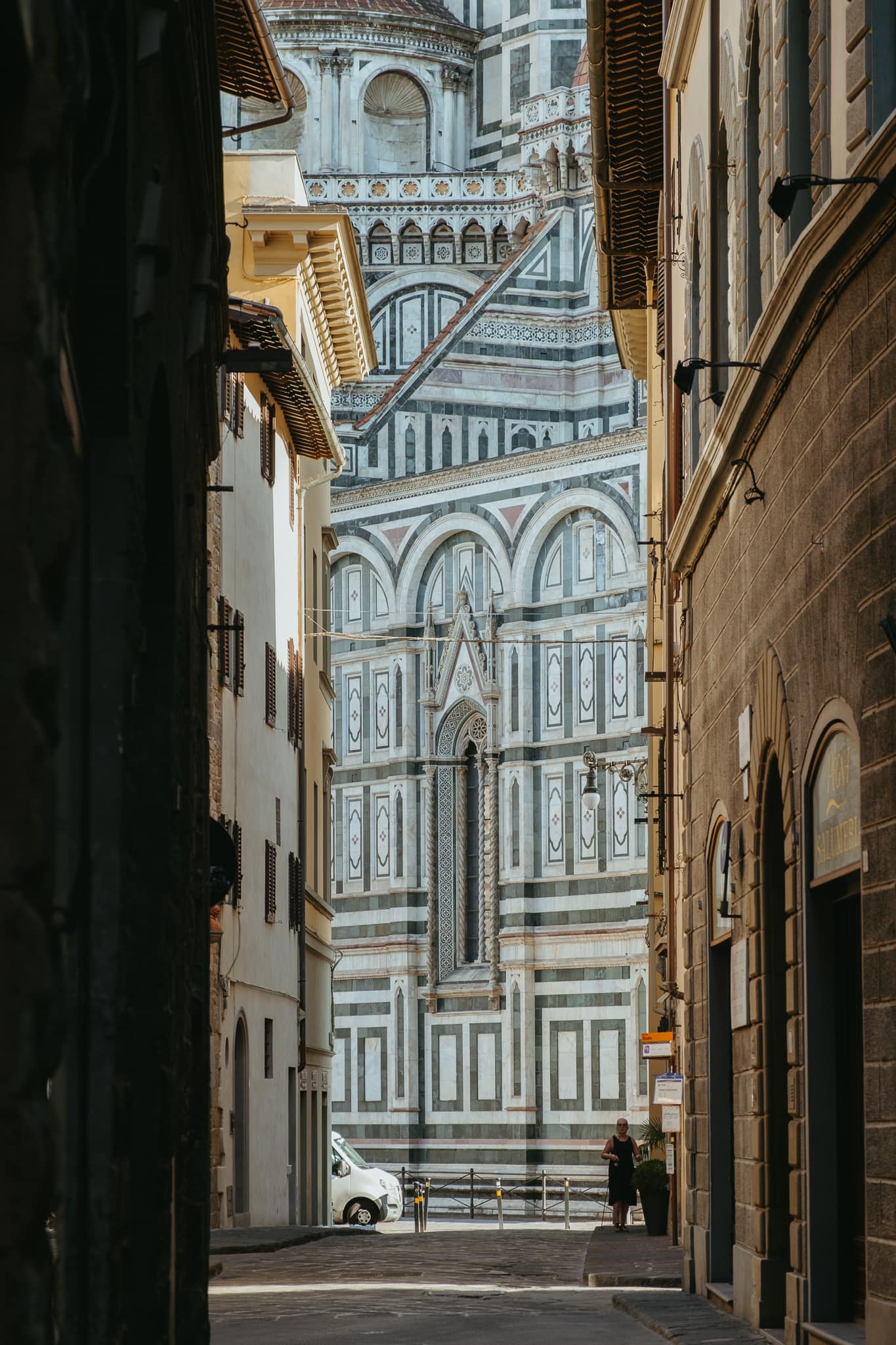 The marble patterns of Florence's Duomo cathedral are visible at the end of a street.