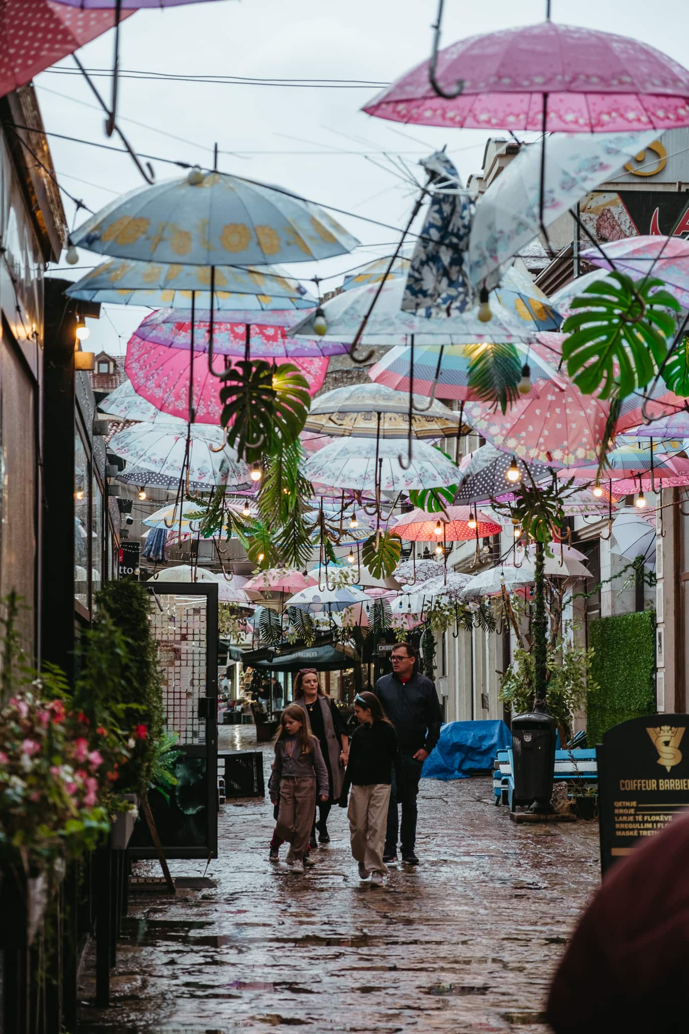A family walks on a street with hanging umbrellas in Skopje.