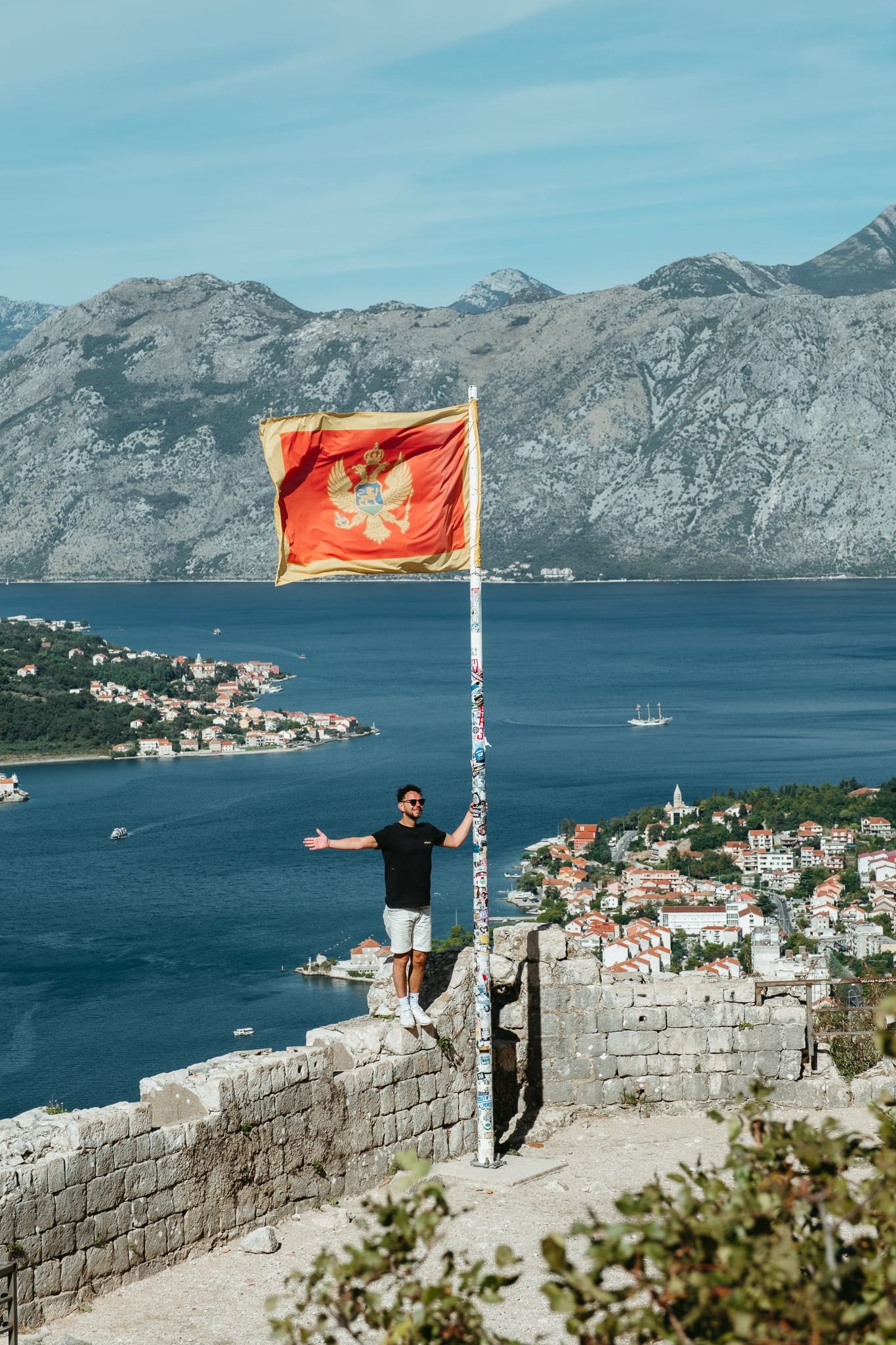 A man poses with the flag on Kotor Fortress.