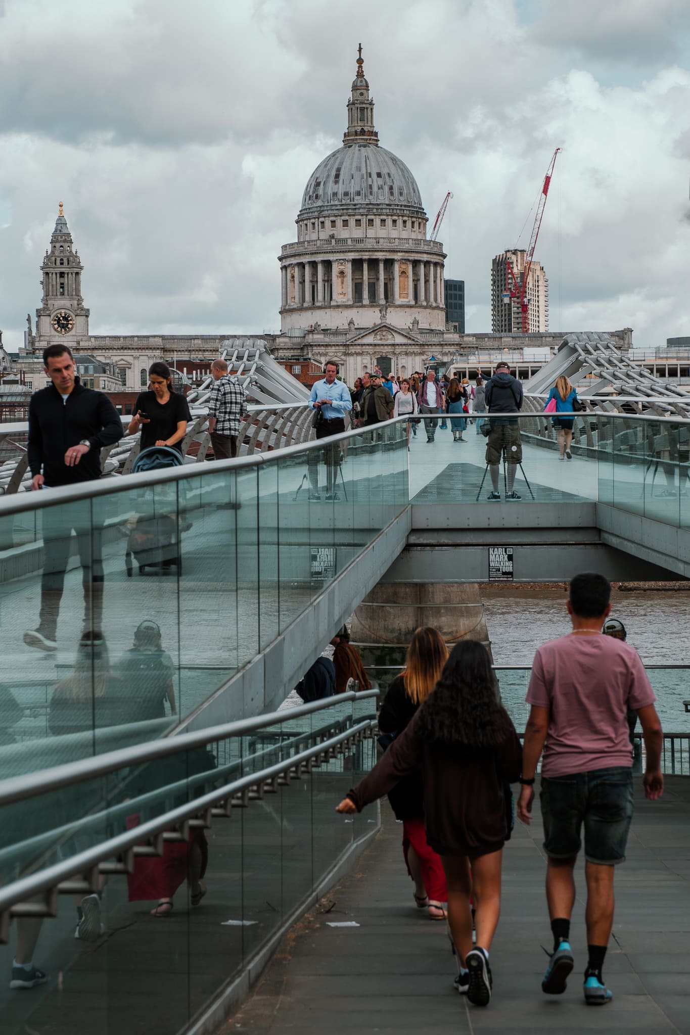 People walk on London's Millennium Bridge, with St. Paul's Cathedral in the background.