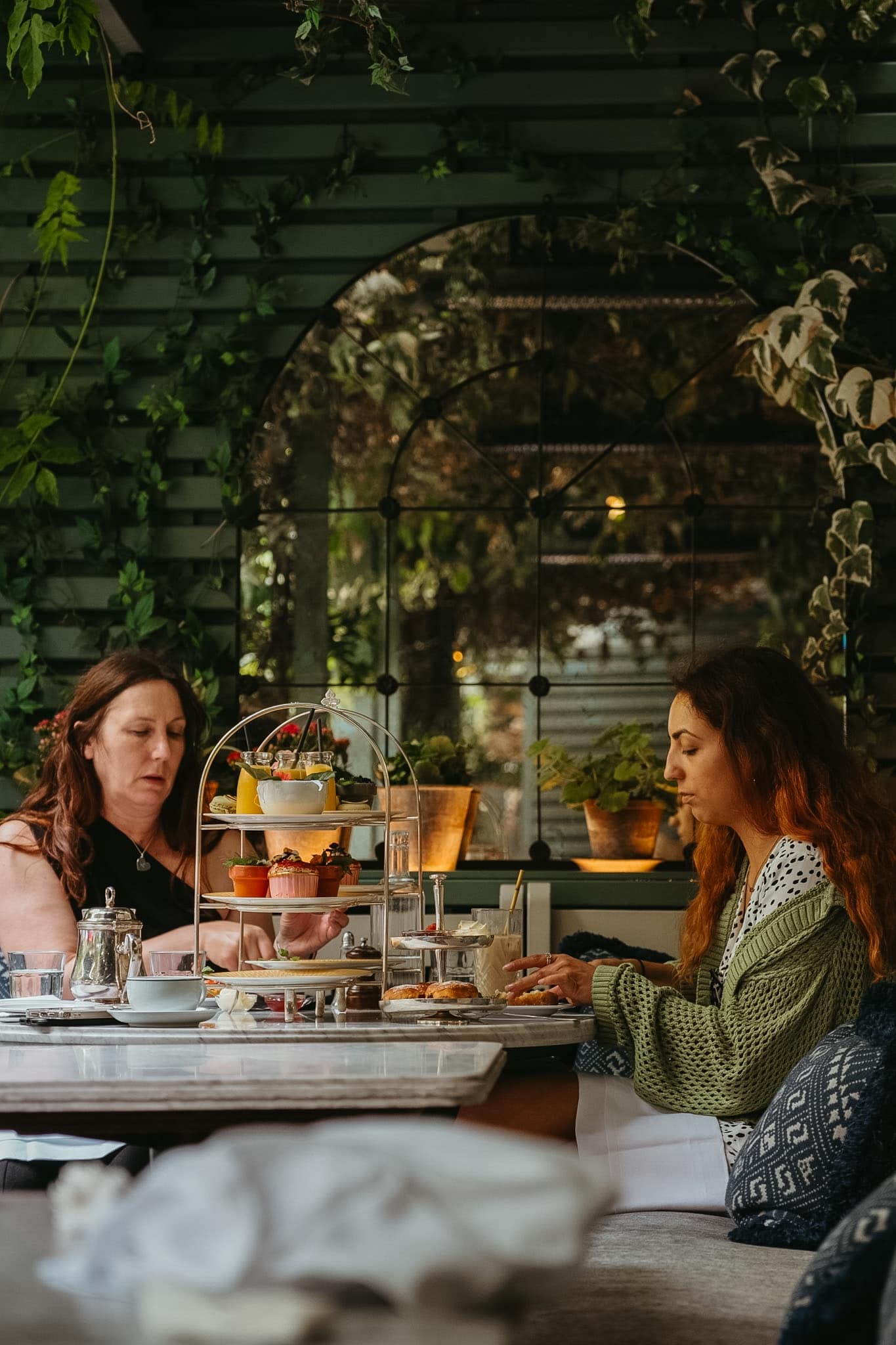 Women eating afternoon tea in the corner of a garden.