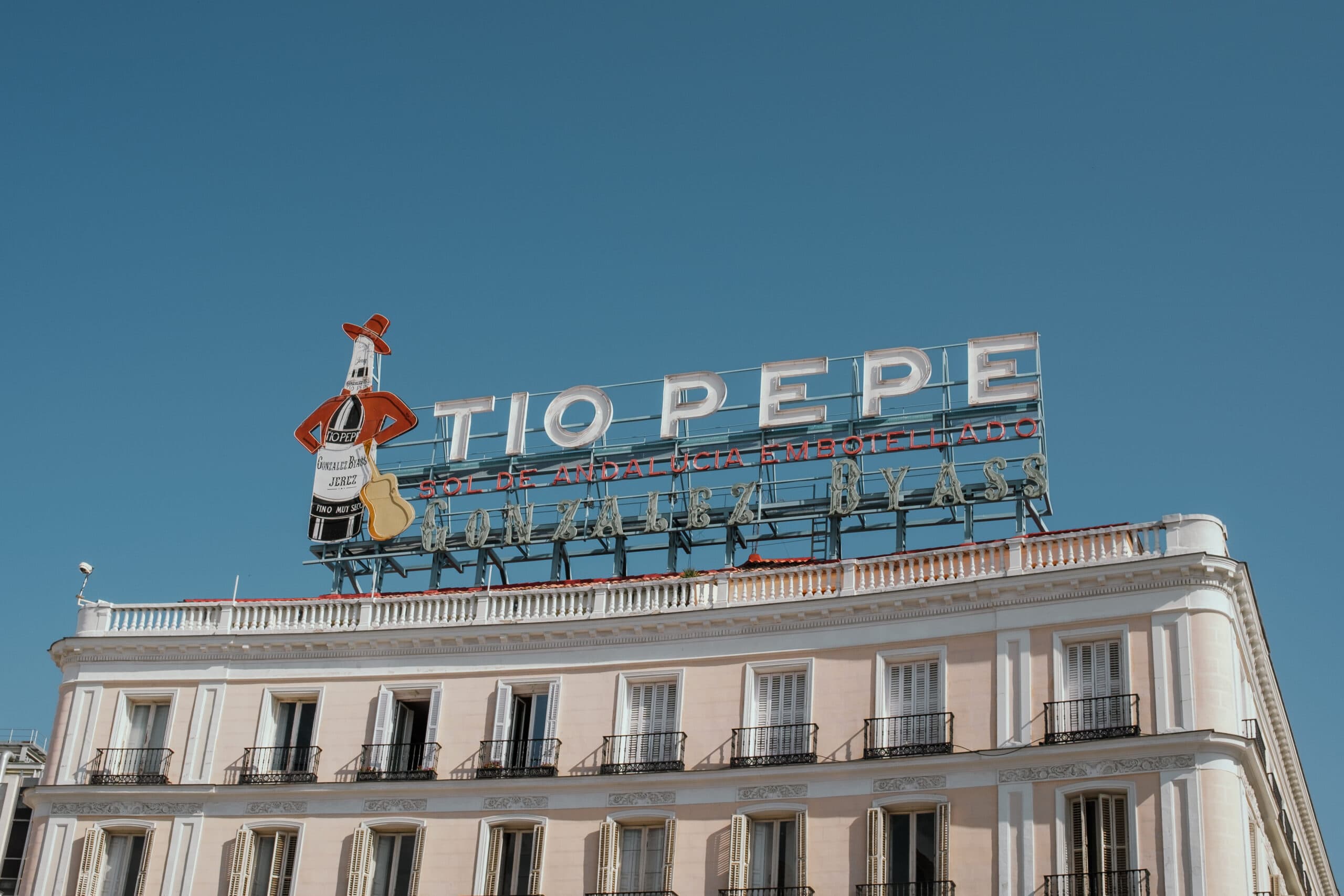 Tio Pepe brand sign sits on top of a building in a Madrid plaza.