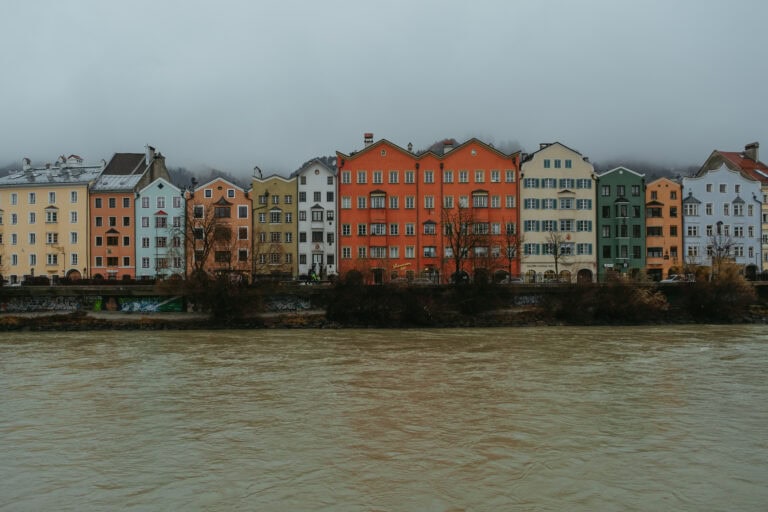 Colorful buildings line a river in Innsbruck.