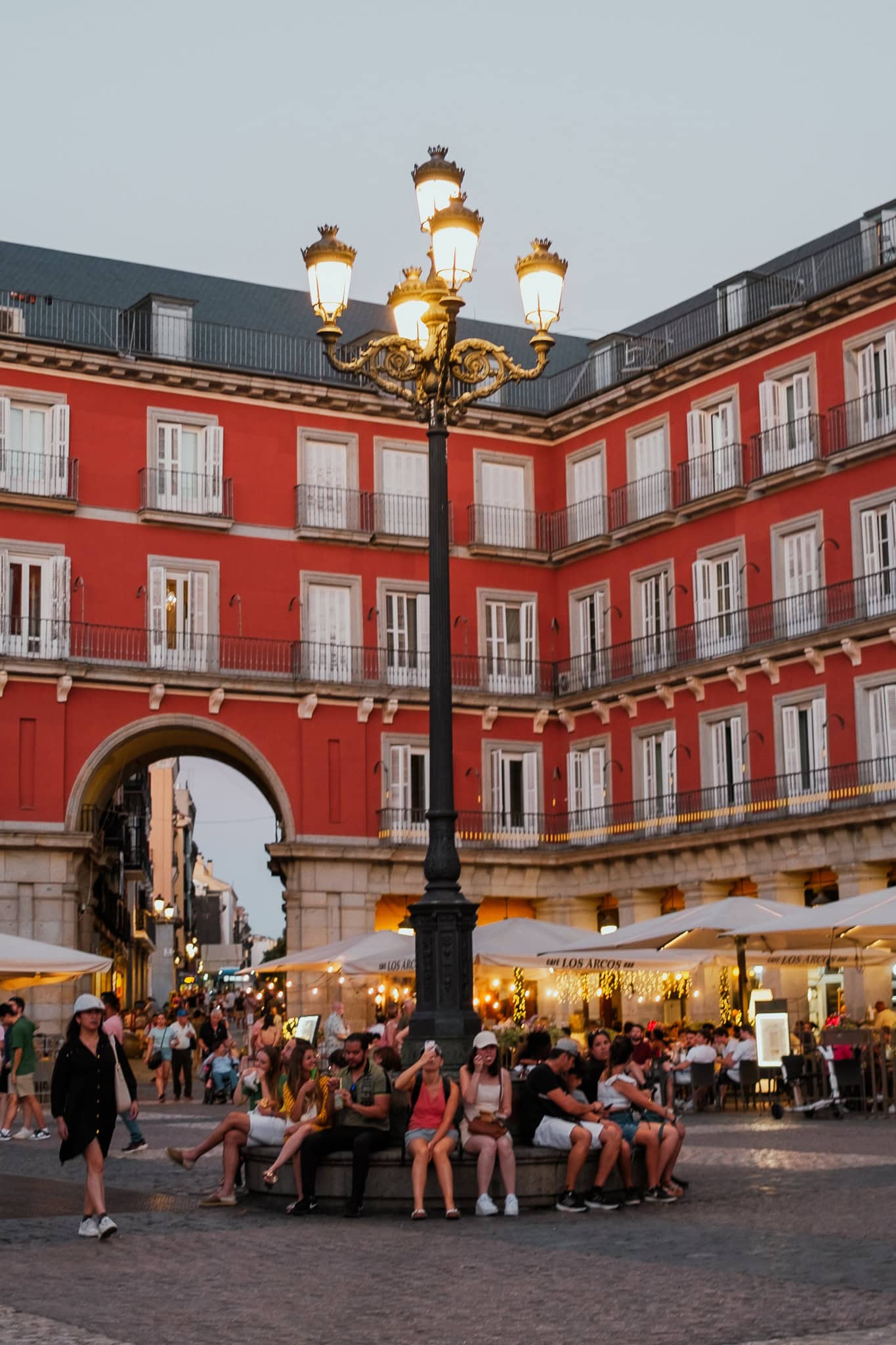People sit around a large lamppost in Plaza Mayor.