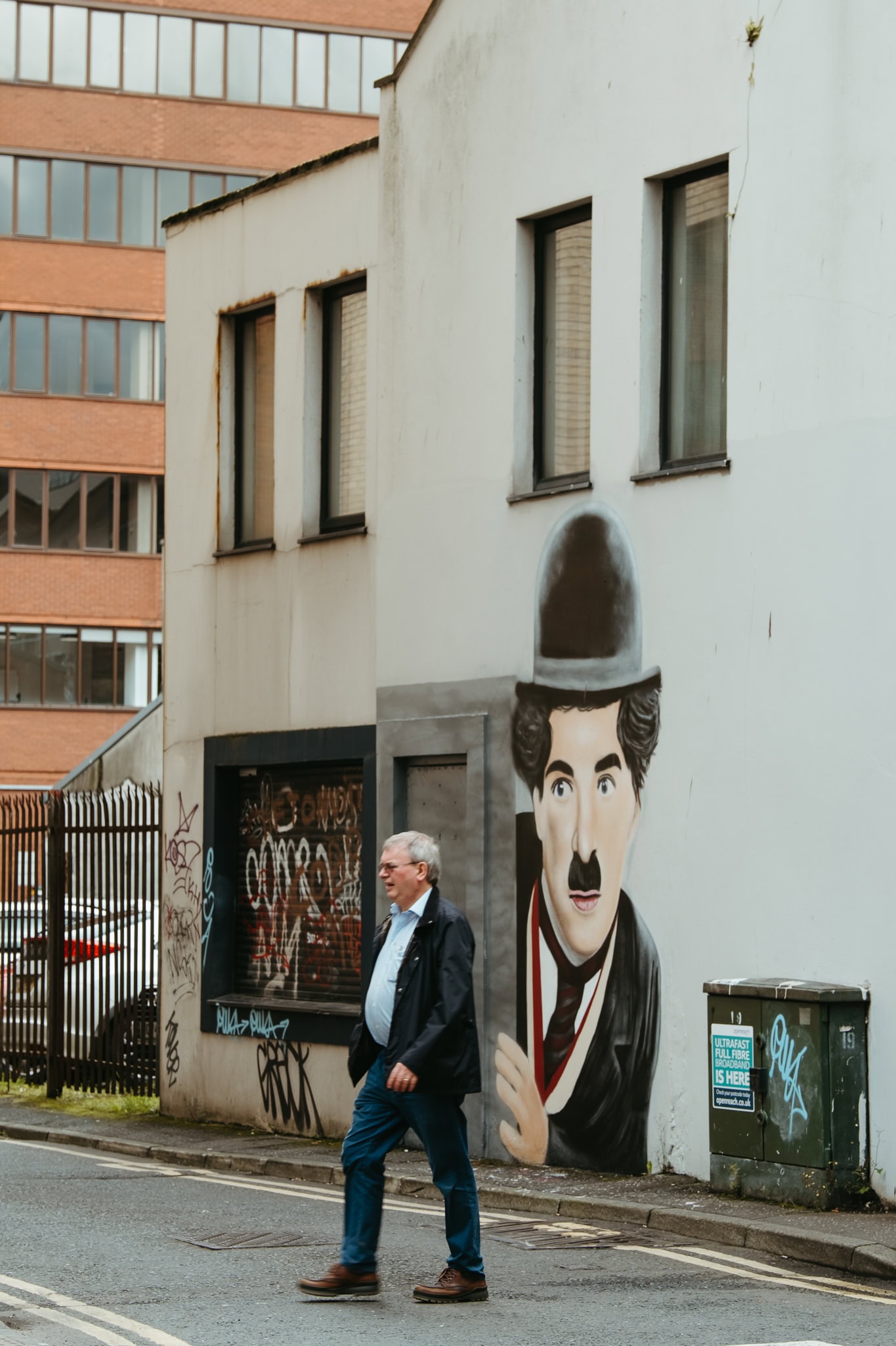 A man walks in front of a mural to Charlie Chaplin.