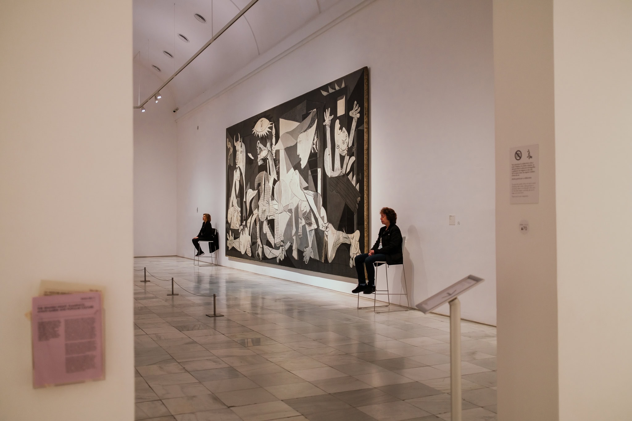 Guards sit beside Picasso's massive Guernica painting.