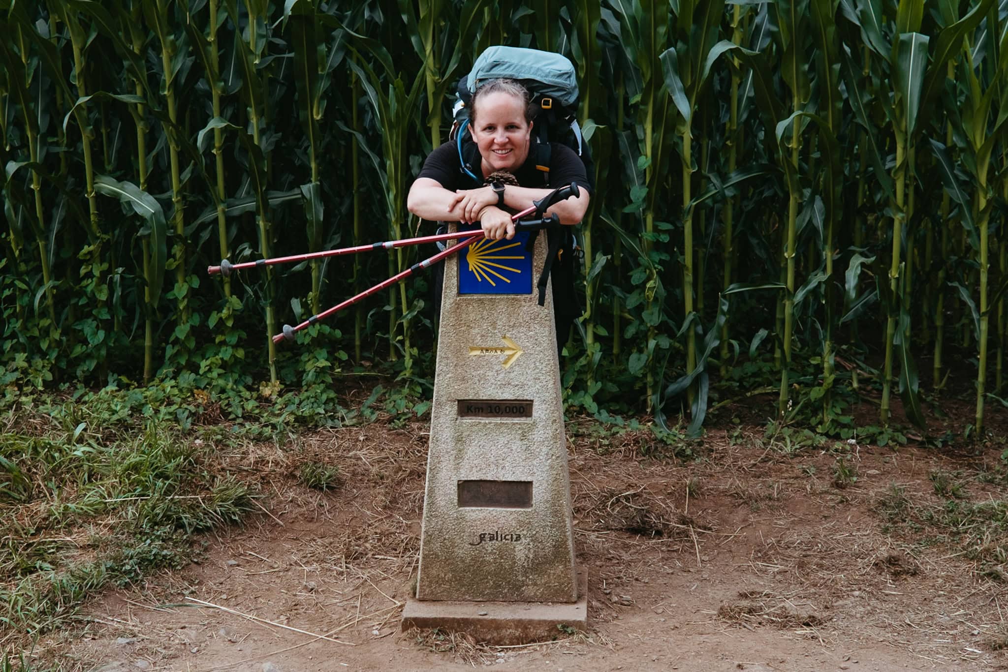 With my backpack on, I stand behind a pillar marking the last 10 kilometers of the Camino Frances.