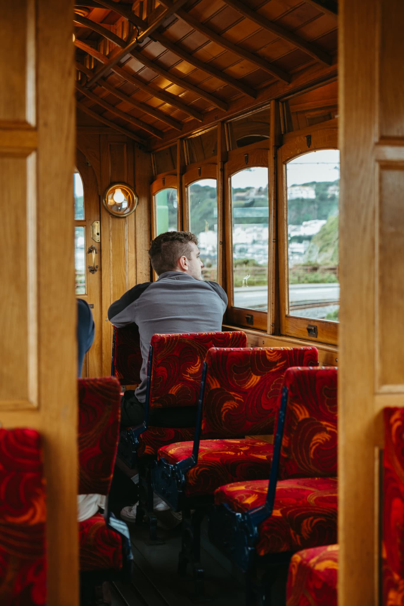 A man looks out the window of a Manx Electric Railway car.