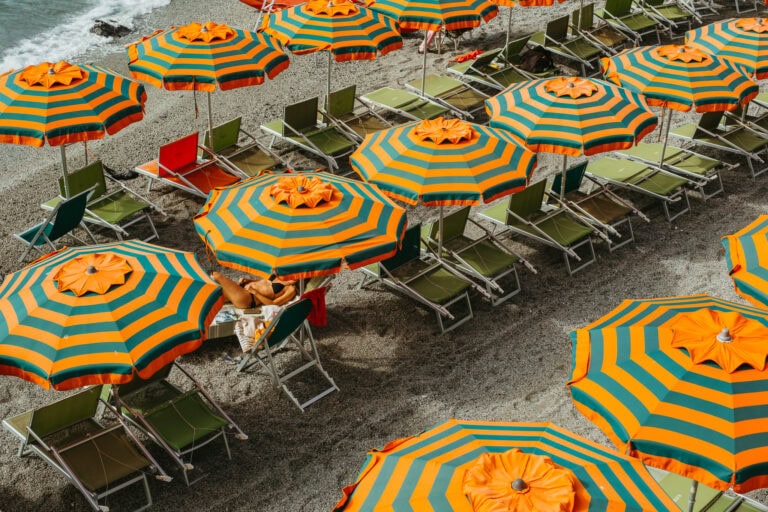 Rows of orange and blue striped umbrellas above beach chairs.