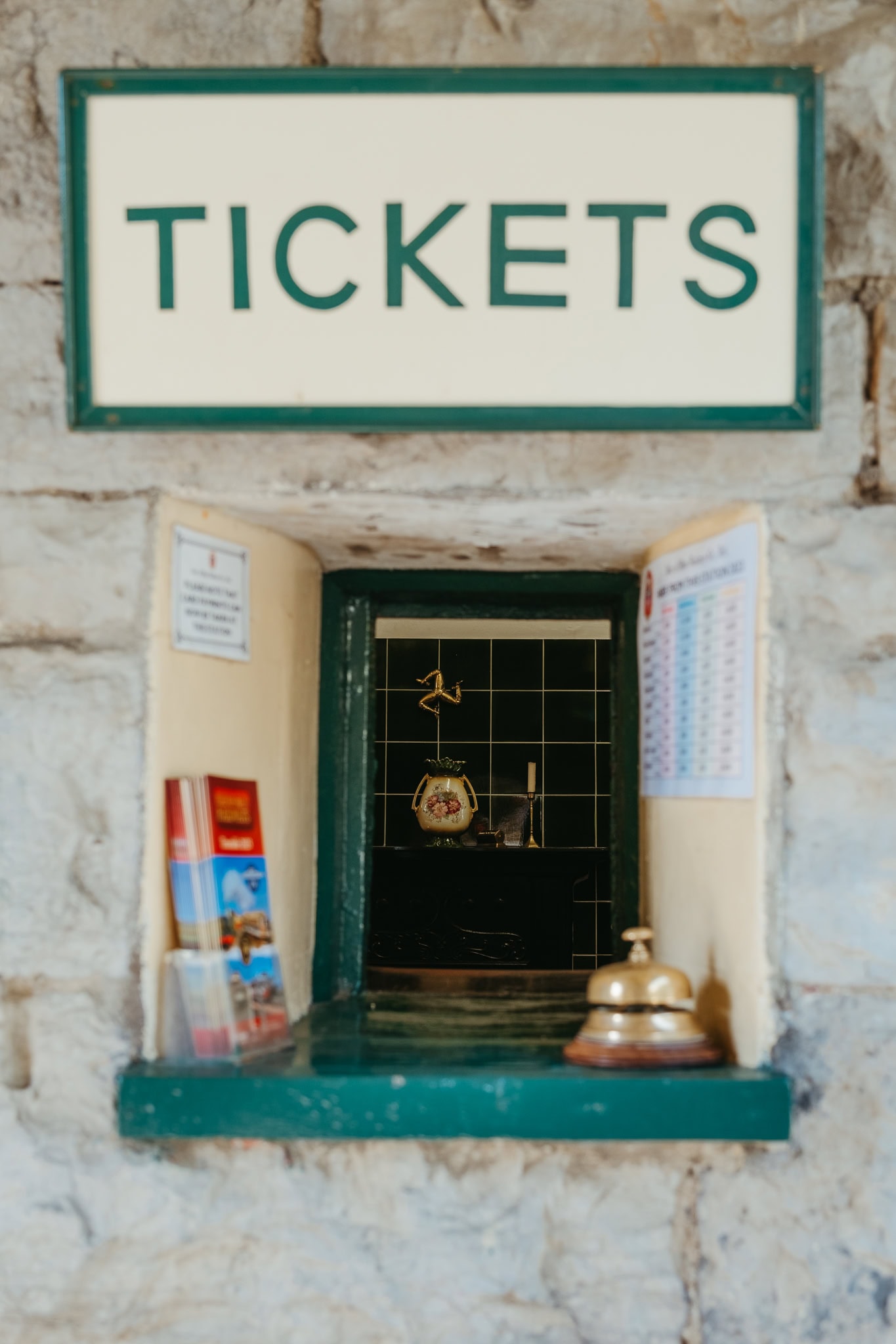 The ticket window in Castletown, where a bell, Manx triskelion symbol, and time table can be seen.