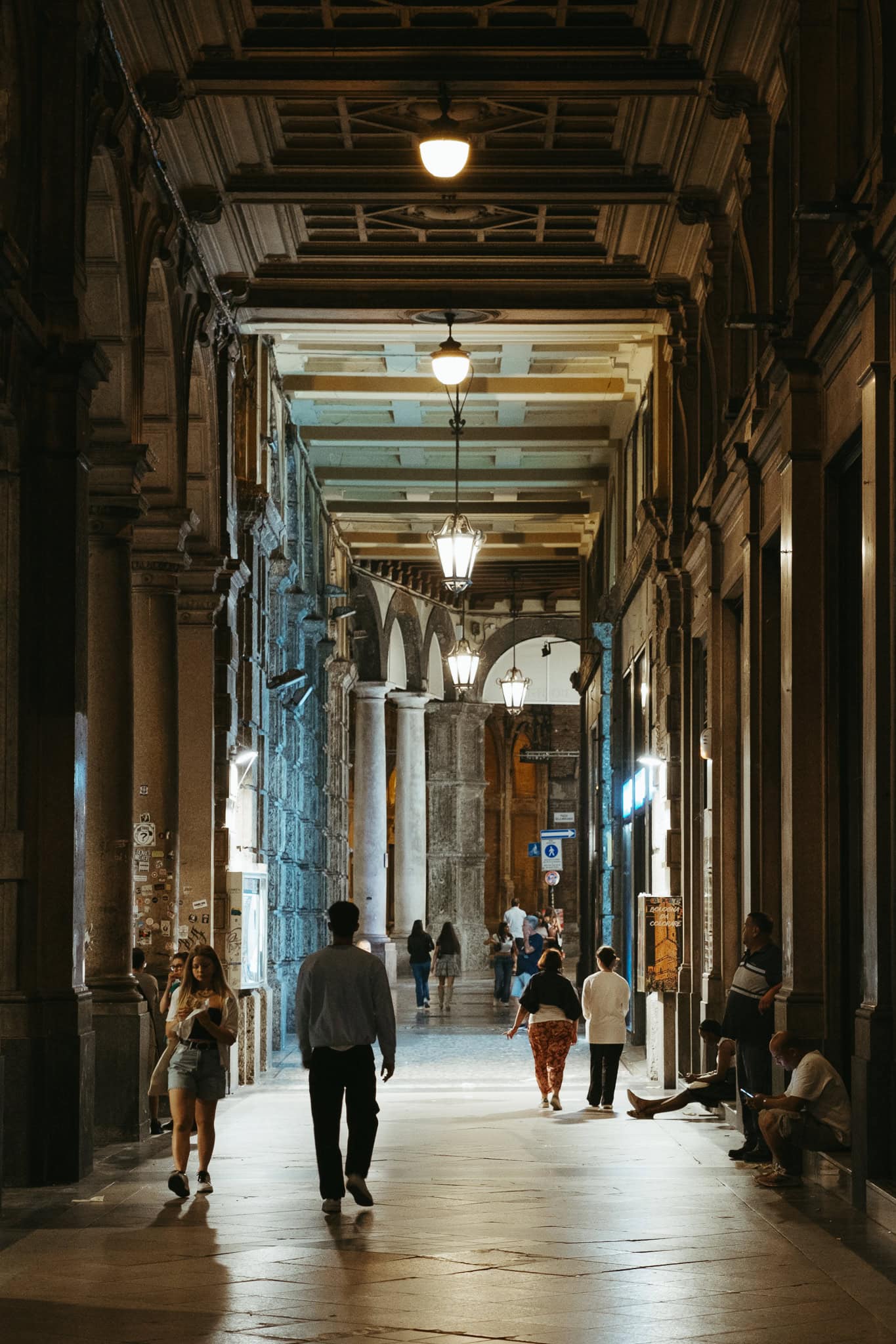 People walk under a portico at night.