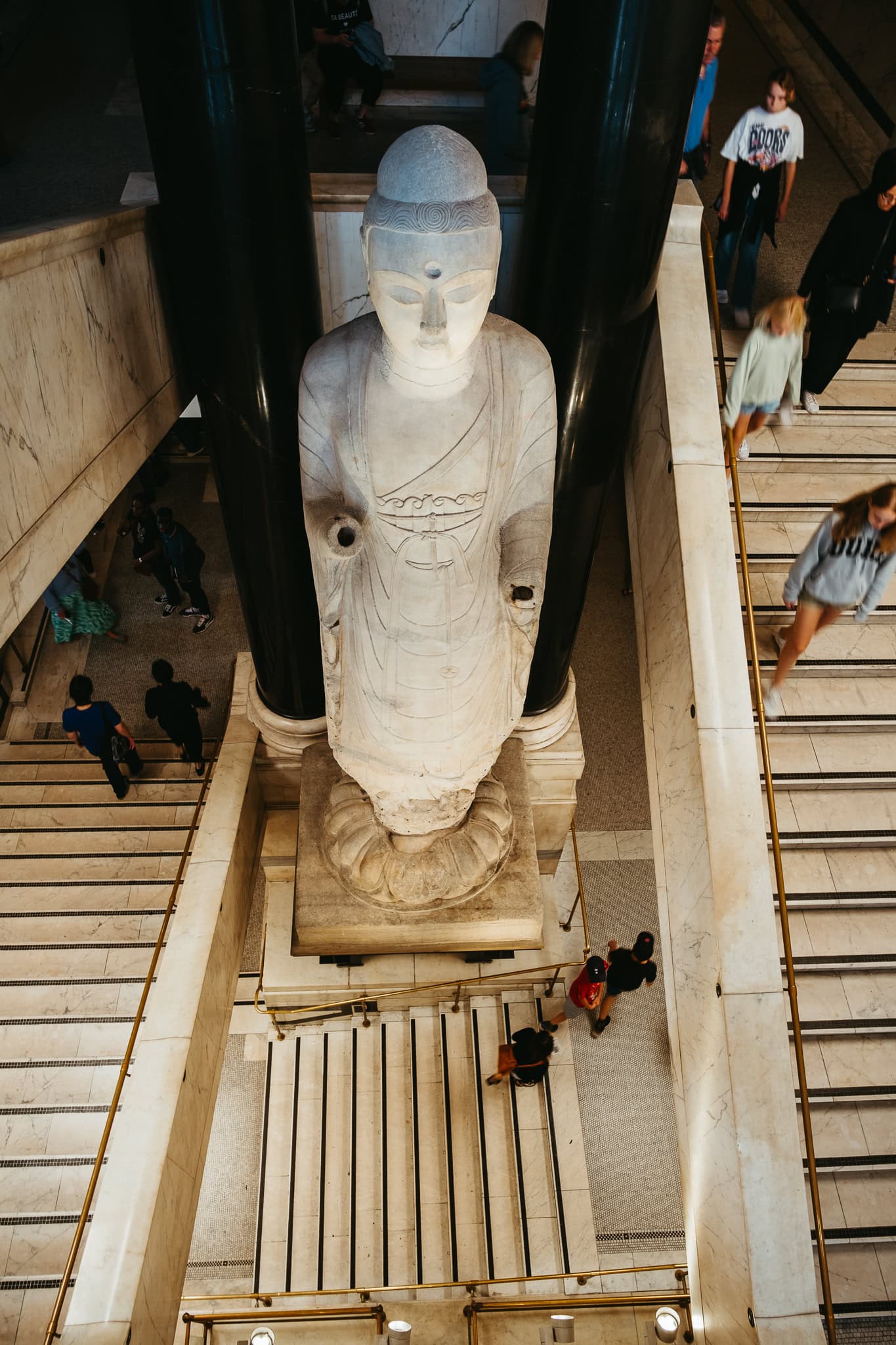 A large statute of Buddha in the middle of a twisting stairwell.