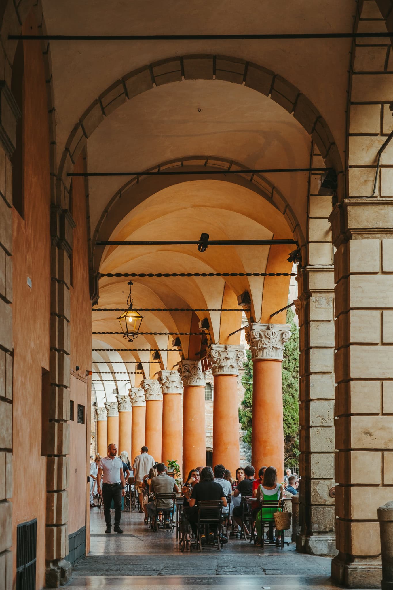 People eating at a restaurant under a Bologna portico.