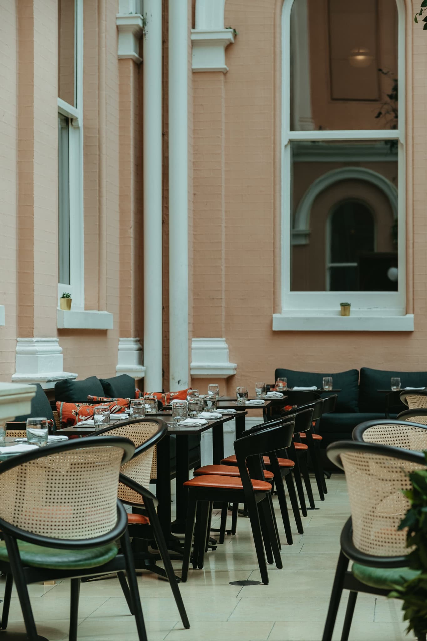 Chairs and tables within a peach-colored interior courtyard.