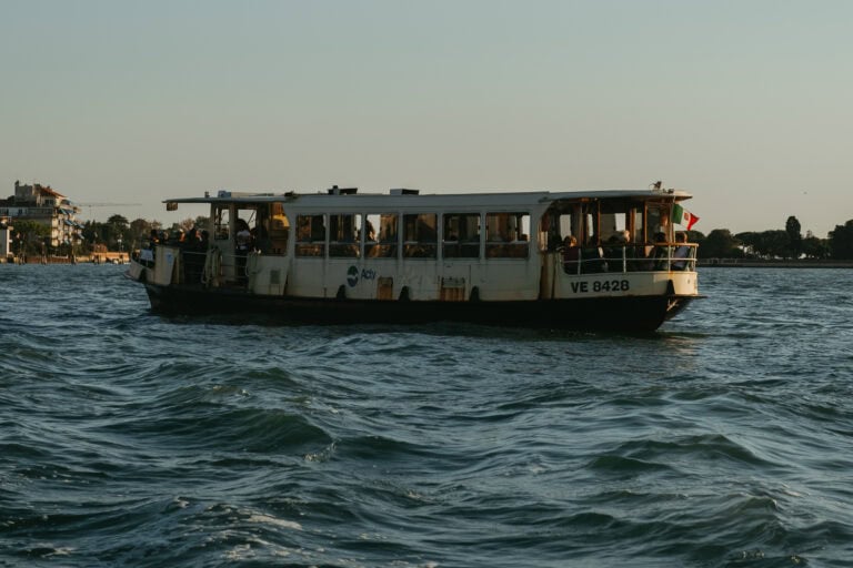 A full vaporetto on the water during golden hour.