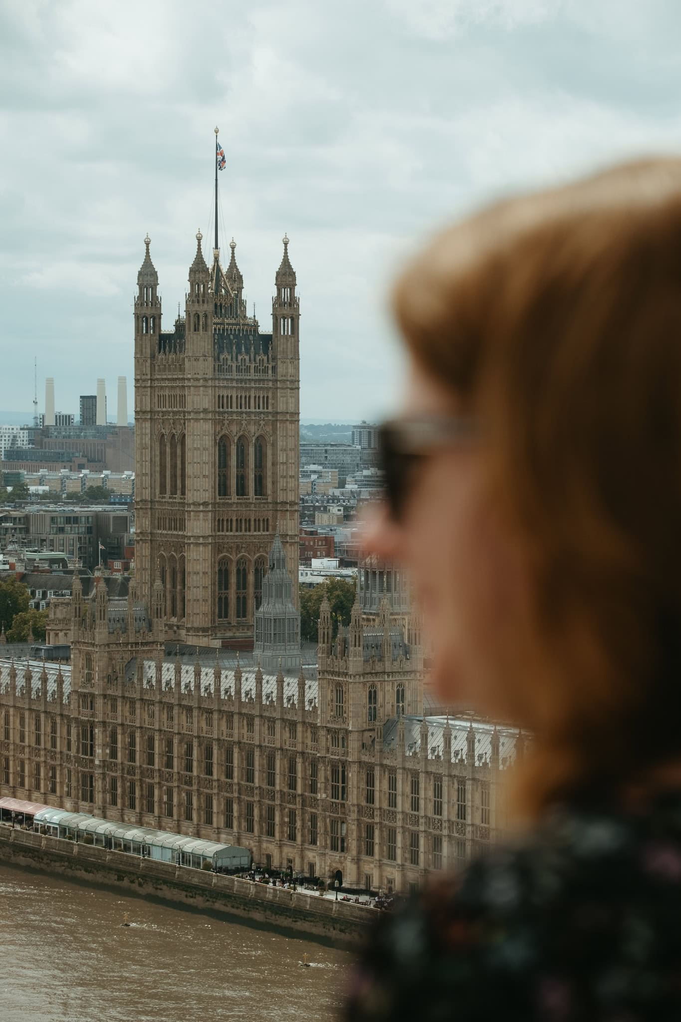 A woman's profile is blurry in the foreground; the Houses of Parliament are clear in the background.