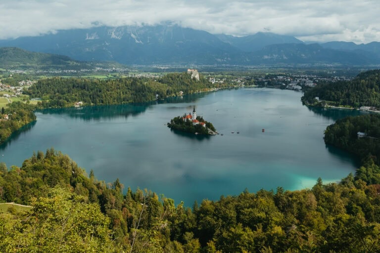 An overhead view of Lake Bled, with Bled Island in the middle, and the surrounding mountains.