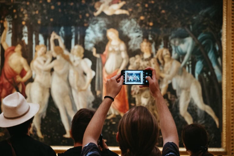 Person taking a photo of Botticelli's Primavera in the Uffizi Gallery.