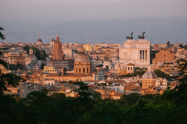 Buildings in Rome glowing at golden hour, as seen from a hill above them.