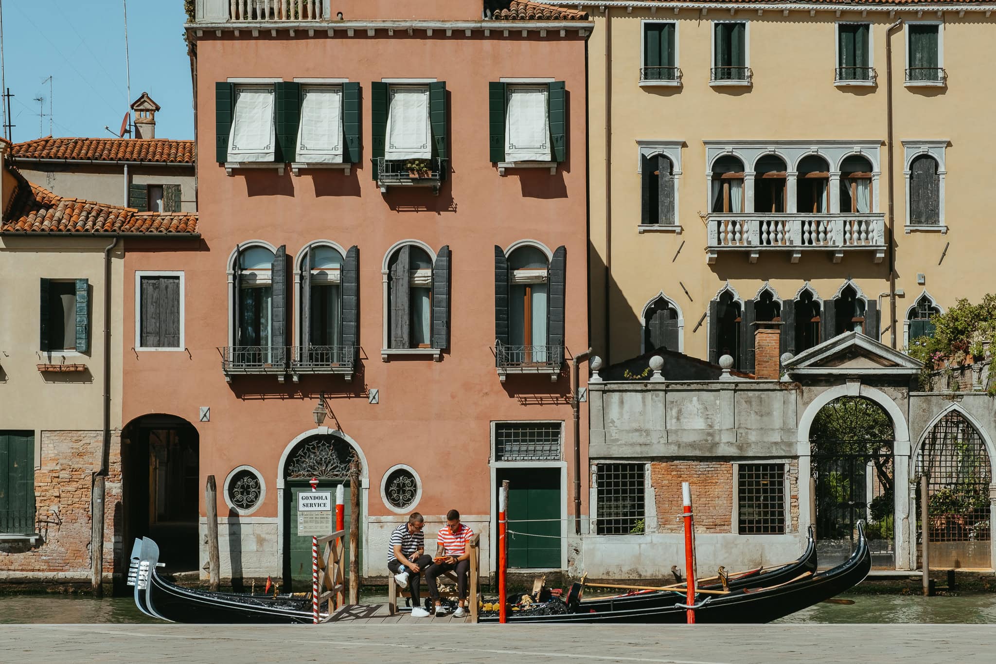 Two gondoliers waiting for customers in front of a gondola stop.