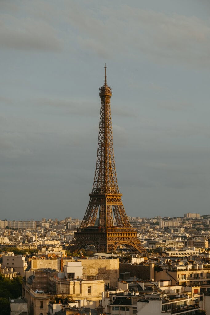 The Eiffel Tower standing above the rooftops of Paris just before sunset.