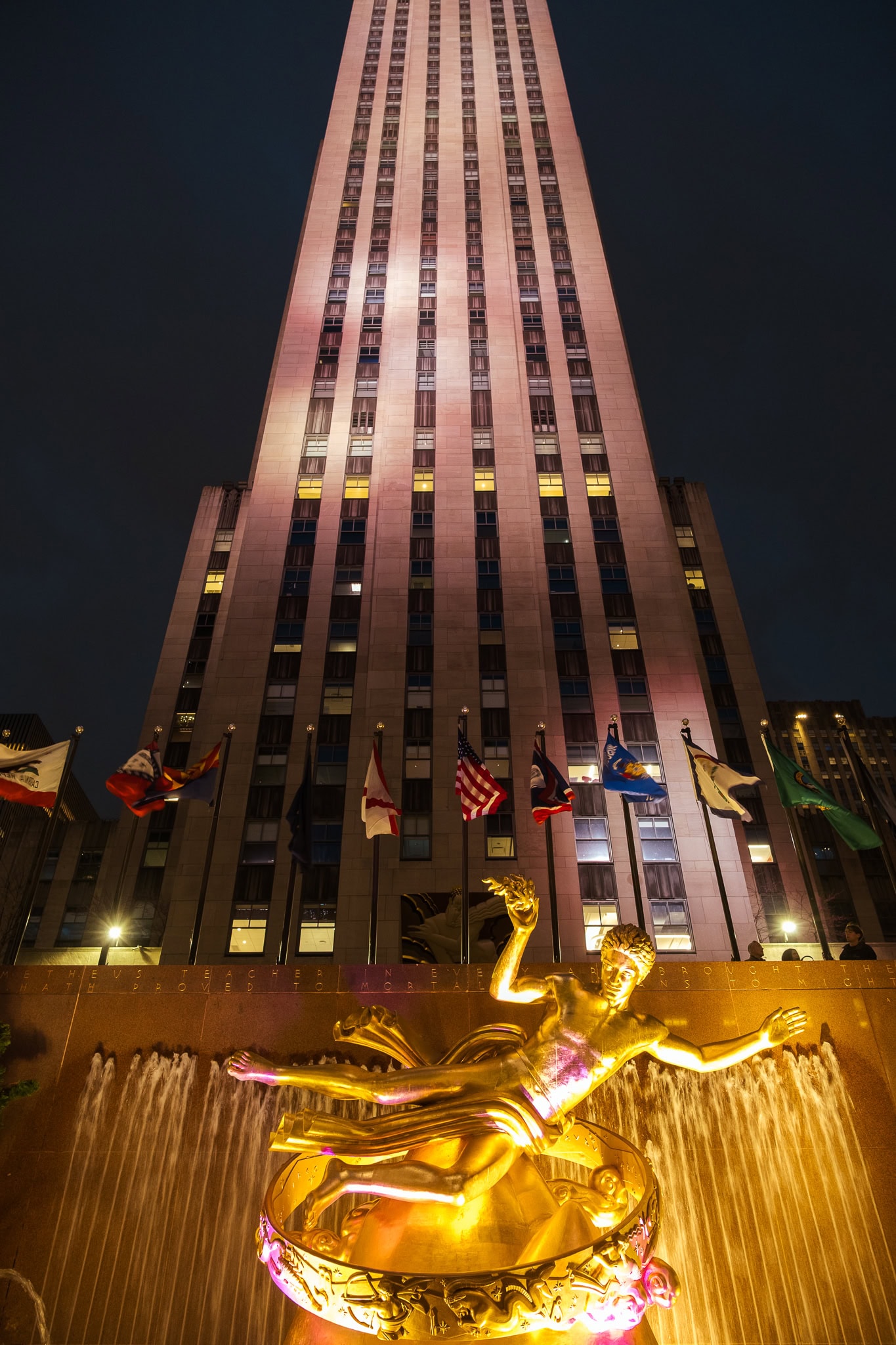 Looking up at a Manhattan skyscraper at night.