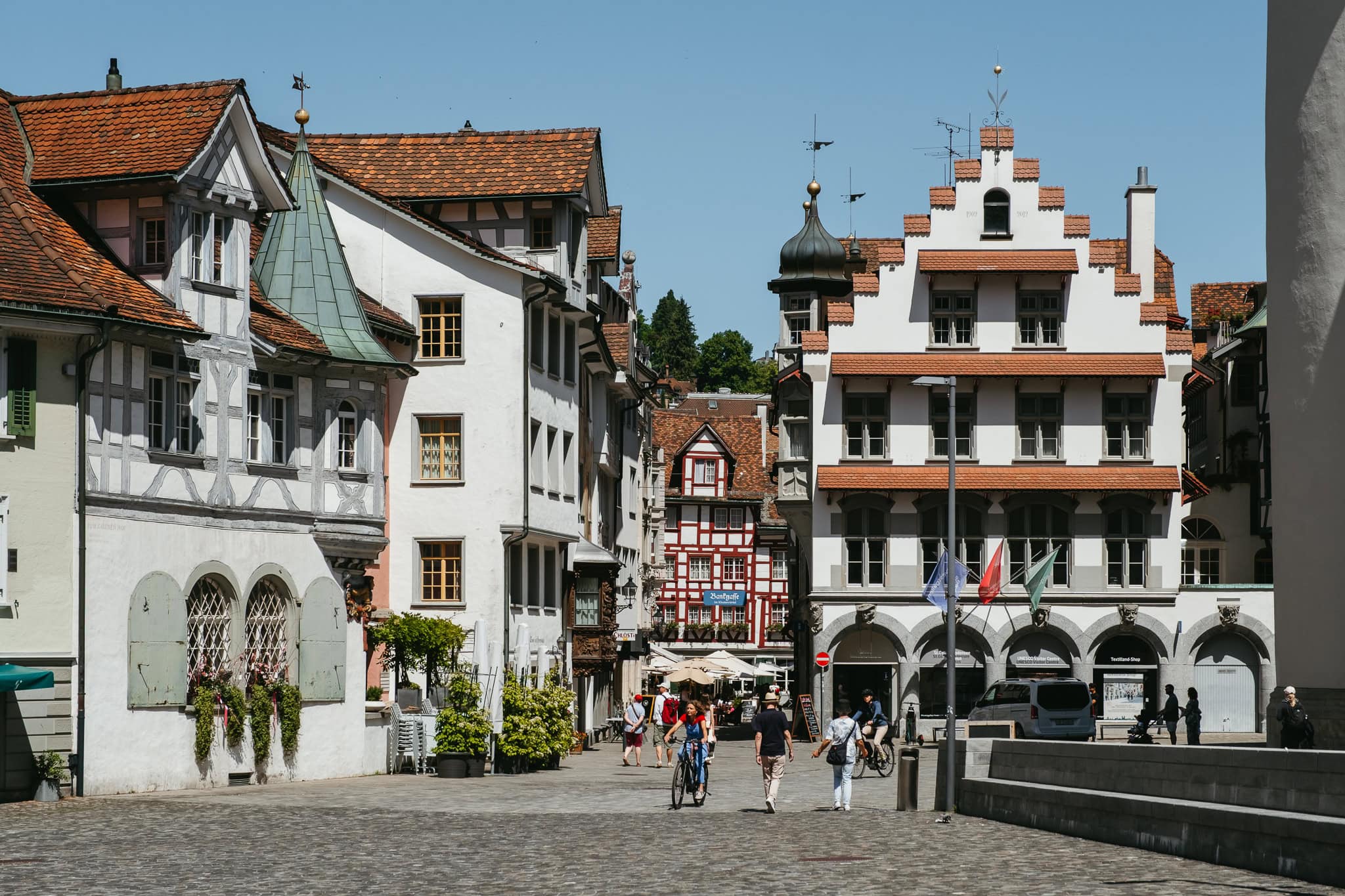 People walking and biking through a square with historic buildings.