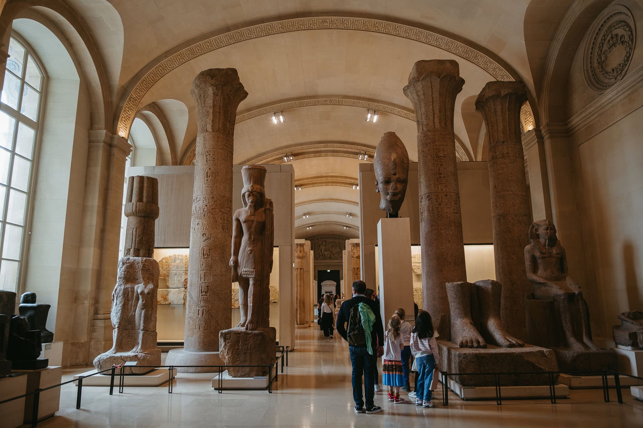 A gallery with columns and Egyptian statues.