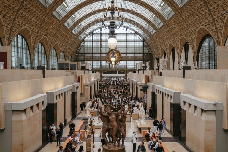 Statues and people fill a large, central museum hall.