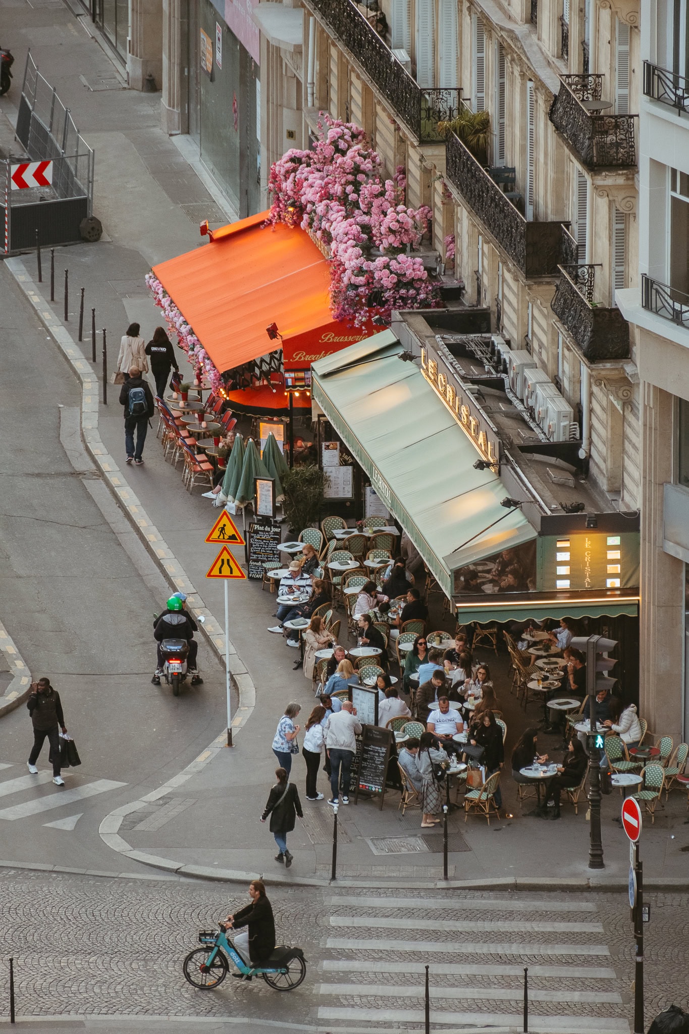 An overhead view of people sitting at two Parisian cafes.