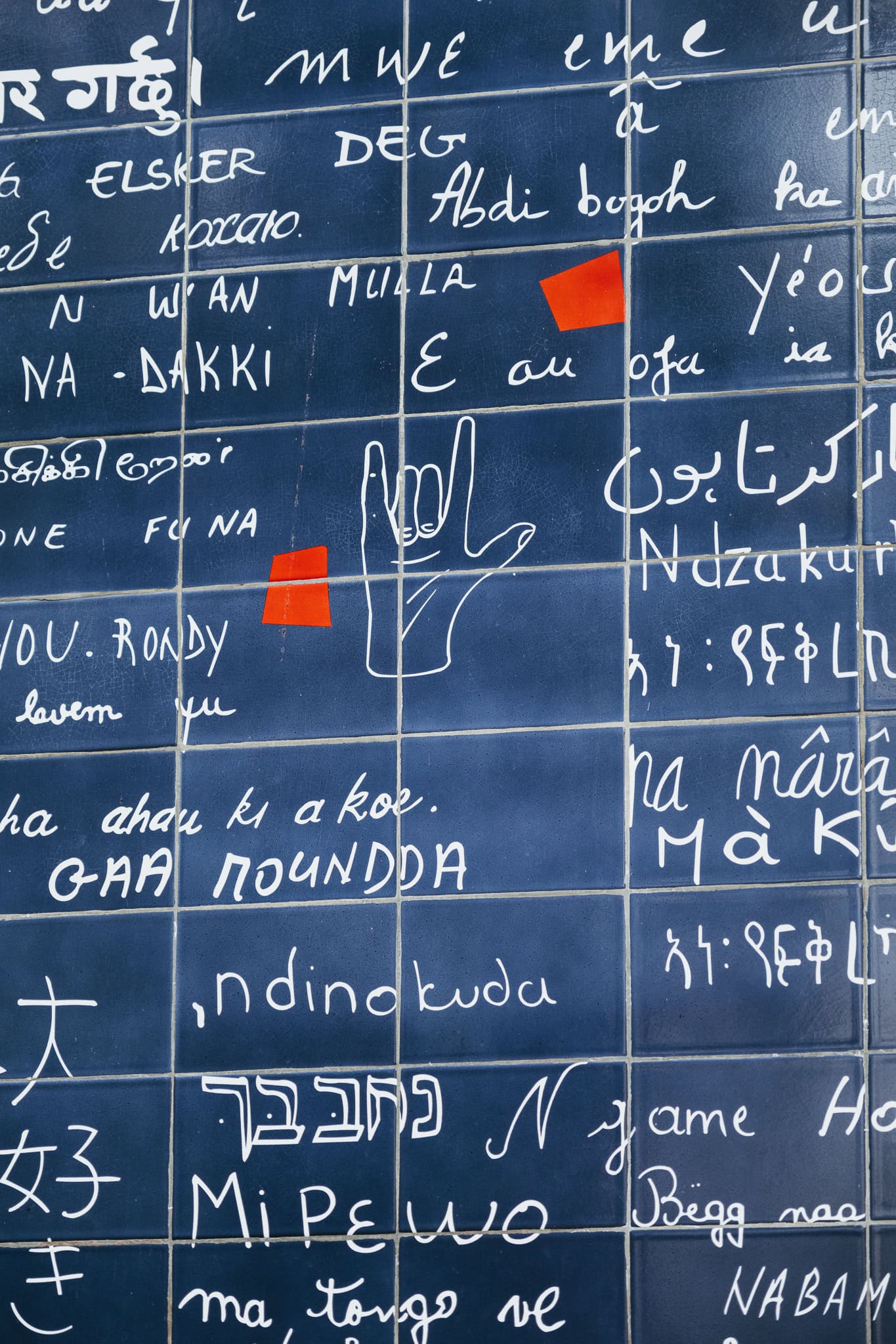 A blue tile wall with many languages printed on it.