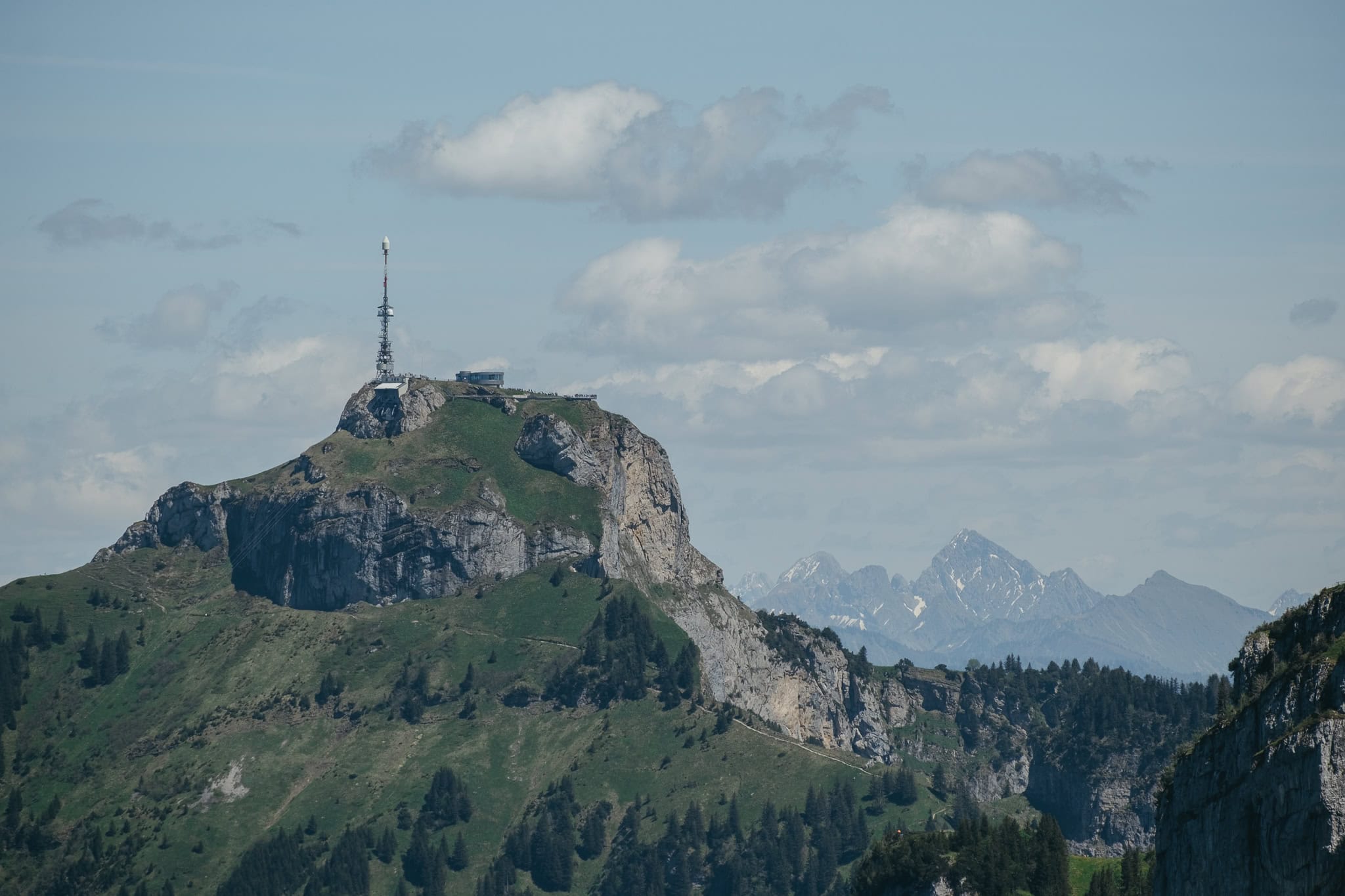 A distant mountain with a tall tower sitting on it.