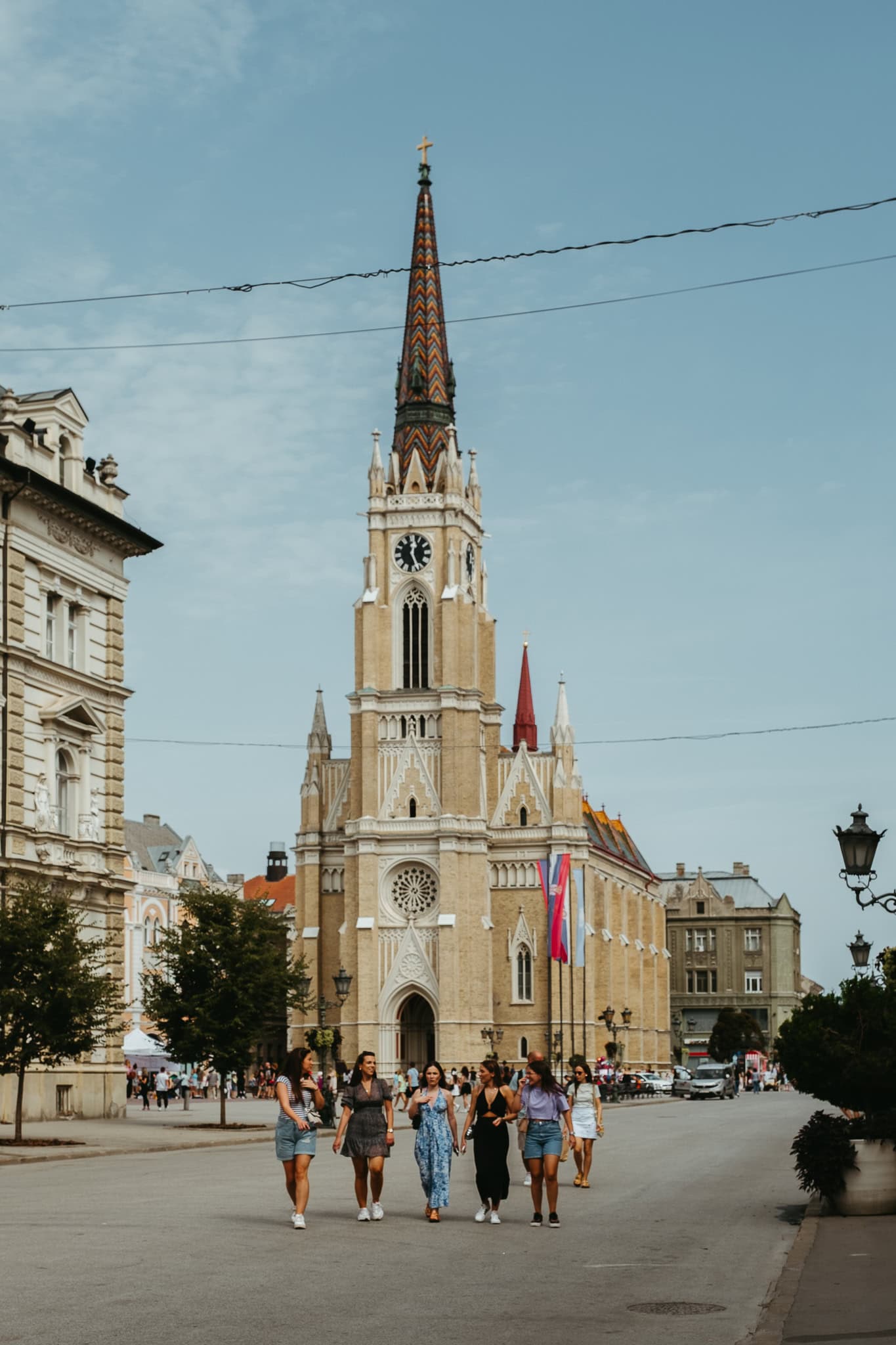 Women walking along a pedestrian street in front of a tall church.