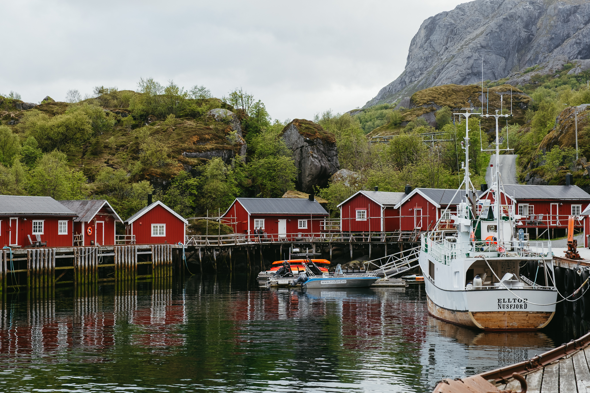 Red cabins sitting around a harbor with a fishing boat.